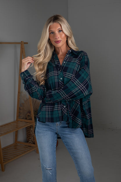 Woman wearing a plaid shirt and jeans standing against a plain background
