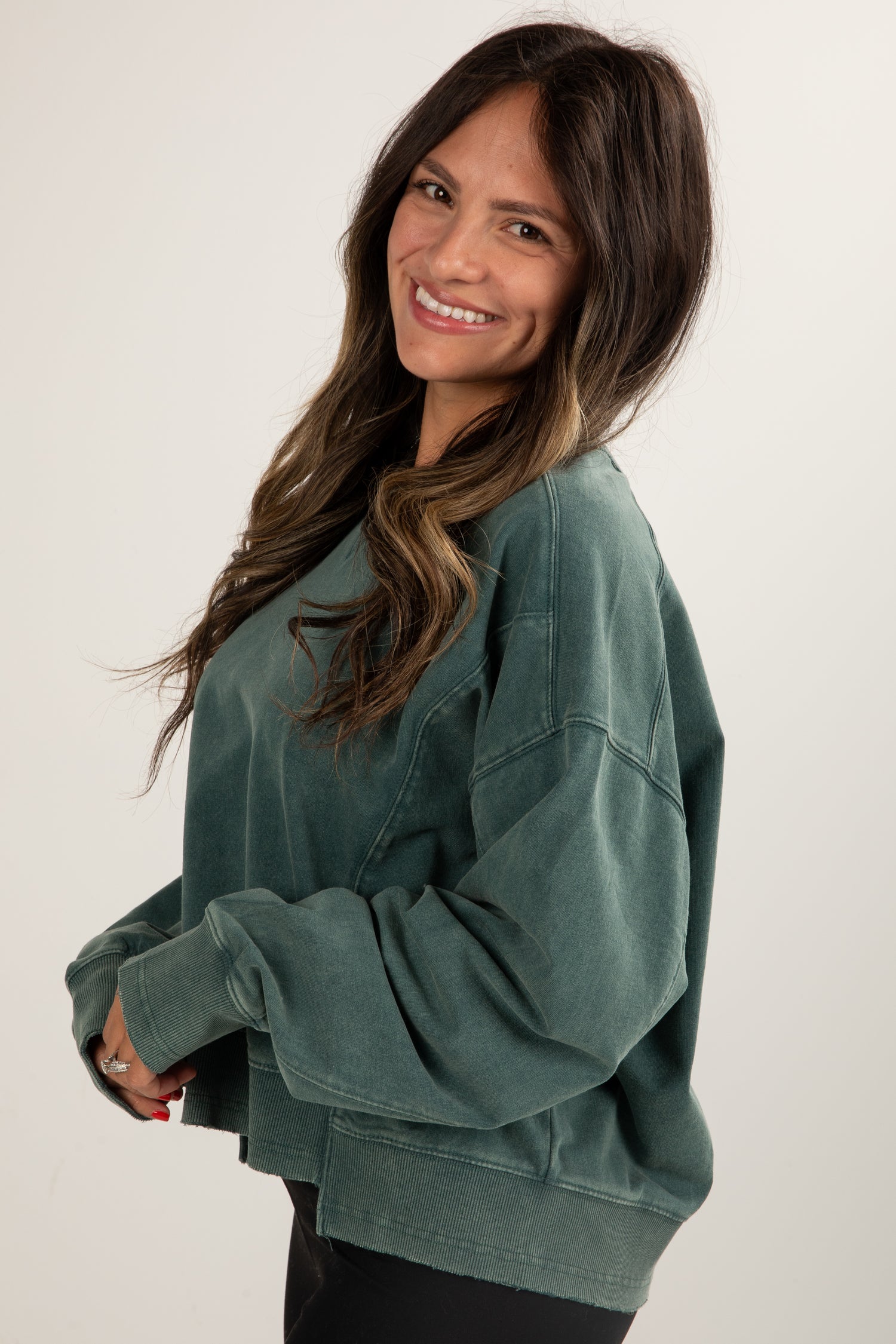 Woman wearing a green sweatshirt against a white background