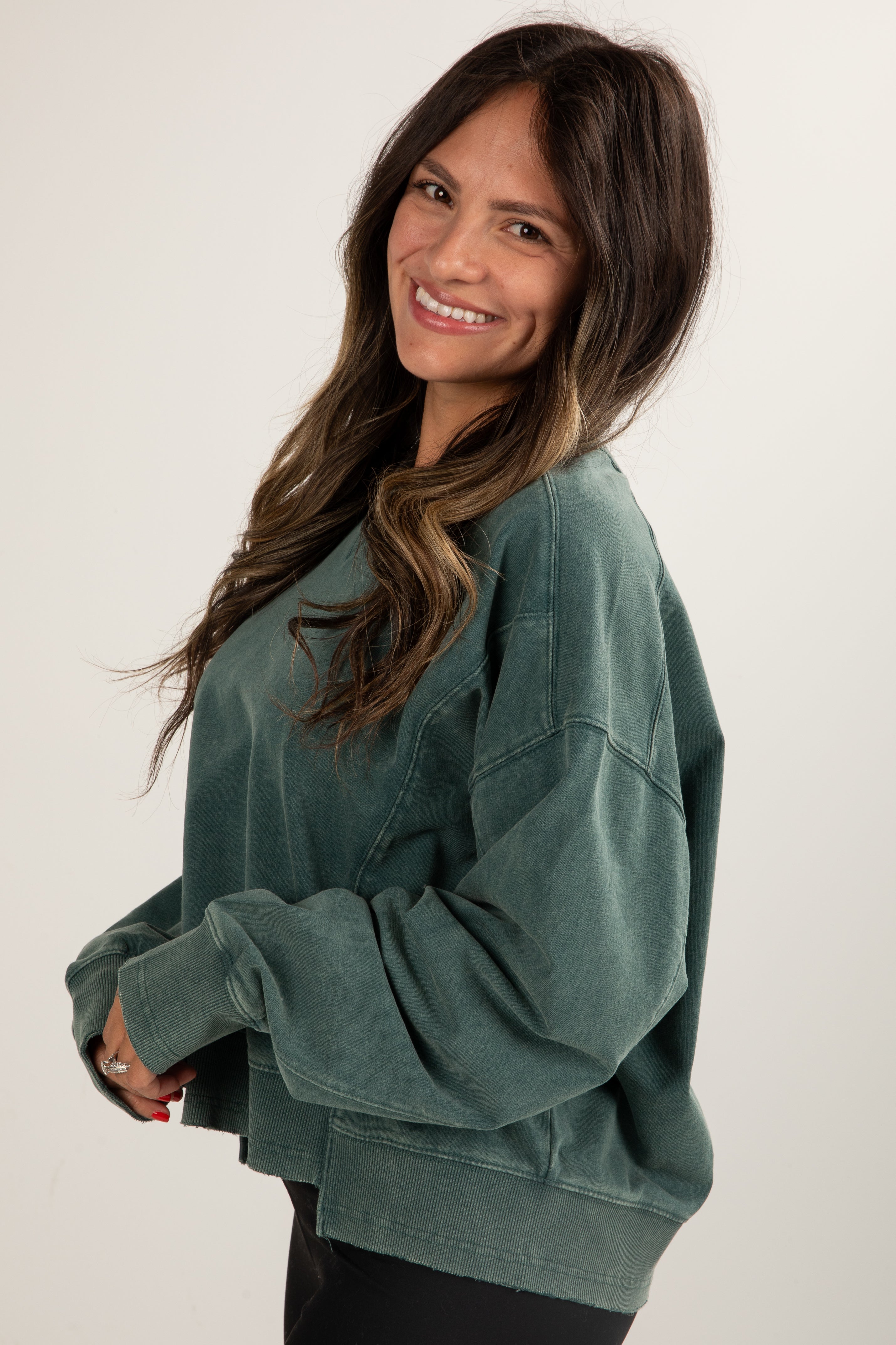 Woman wearing a green sweatshirt against a white background