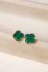 Green clover-shaped earrings on a beige surface