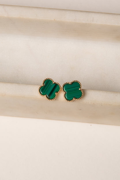 Green clover-shaped earrings on a beige background
