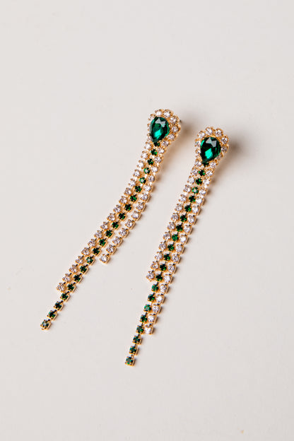 Pair of gold earrings with green gemstones on a light gray background