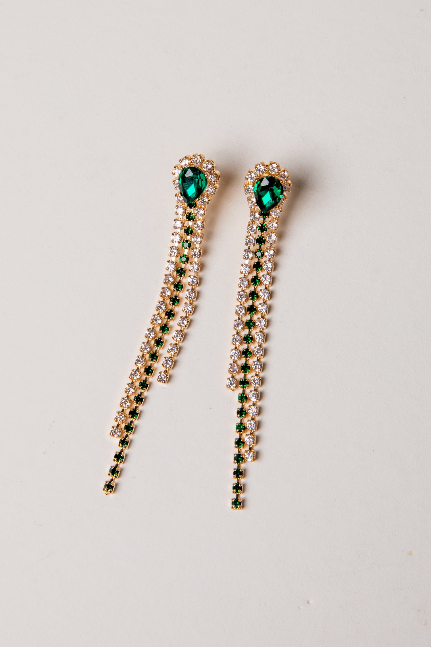 Pair of earrings with green gemstones on a light gray background