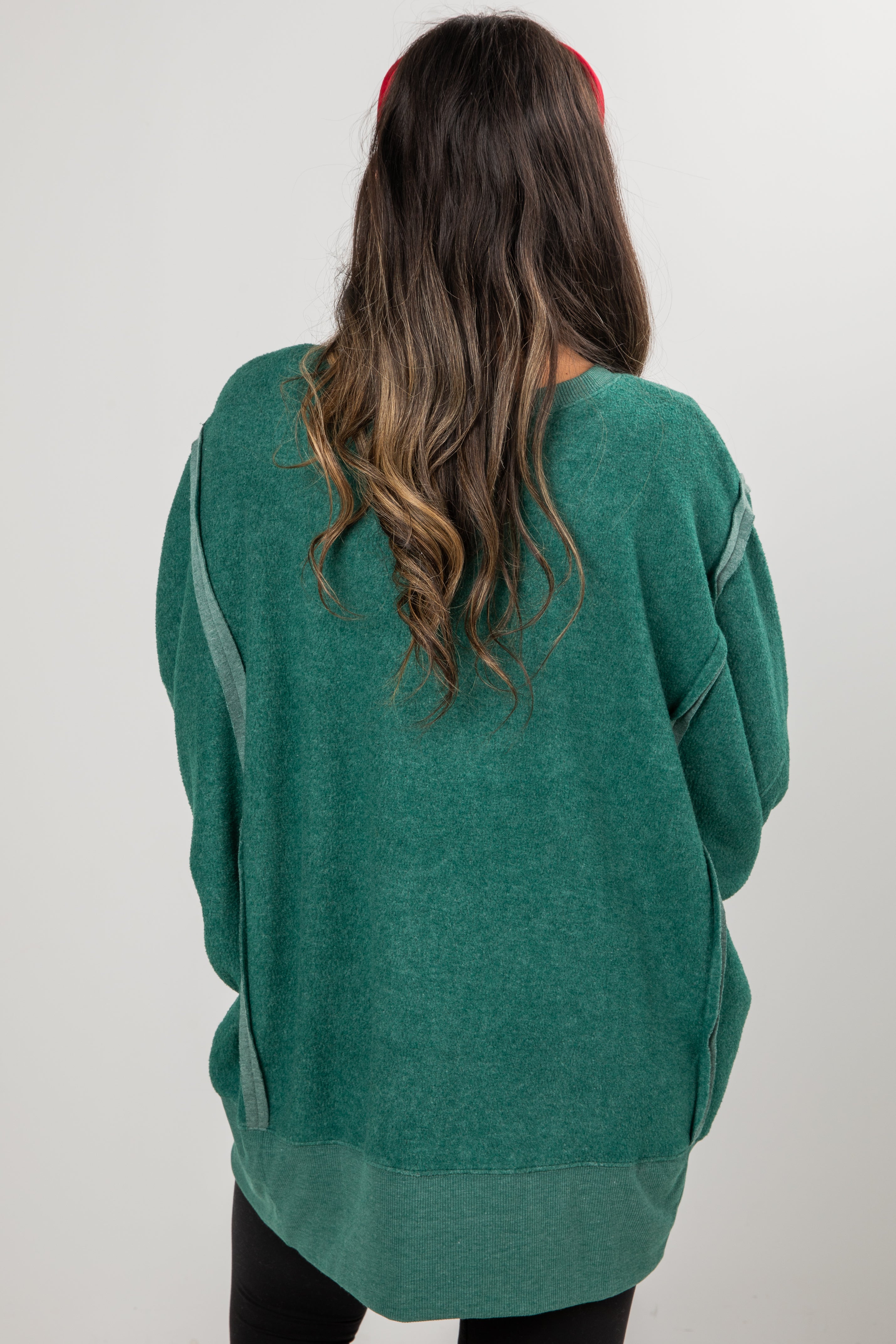 Person wearing a green sweater with gray accents on a plain background