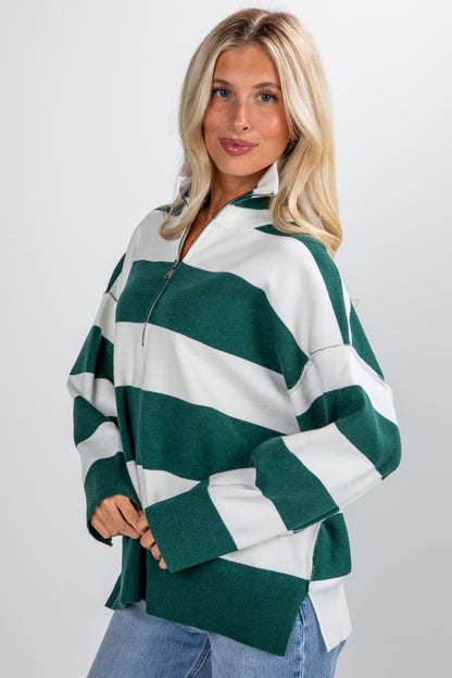Woman wearing a green and white striped sweater on a plain background