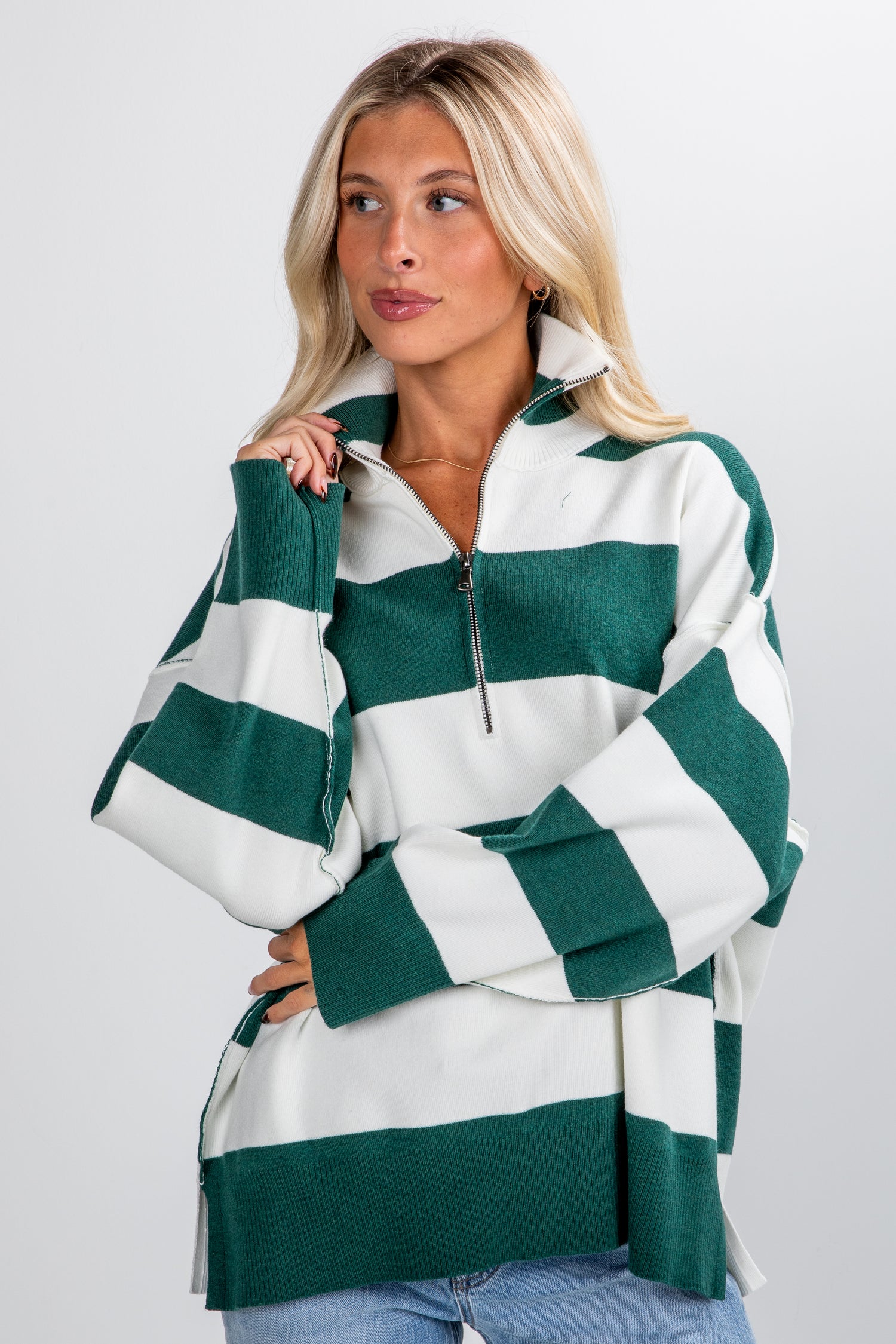 Woman wearing a green and white striped sweater against a plain background