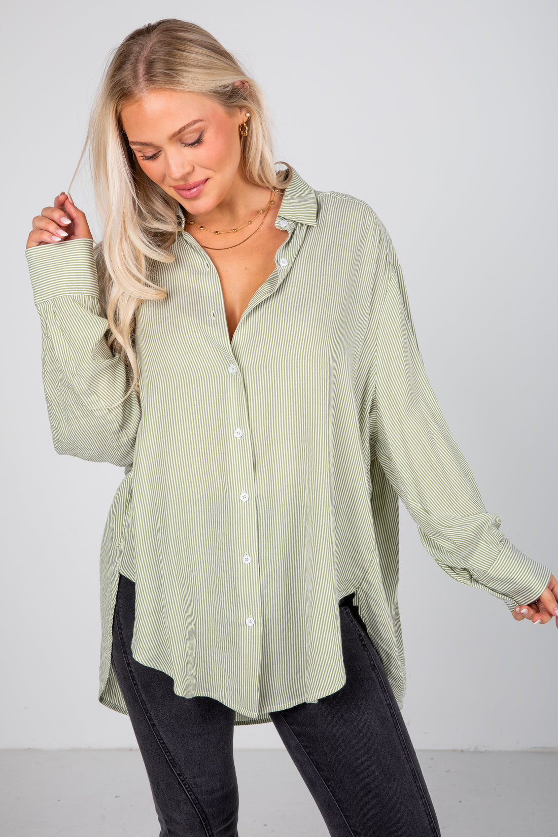 Woman wearing a light green ribbed shirt against a white background