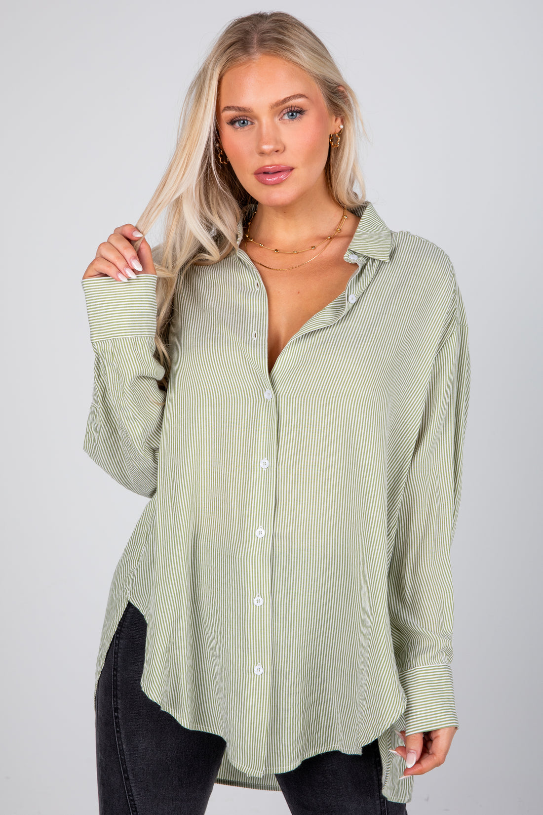 Woman wearing a light green button-up shirt with a plain background