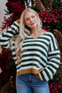 Woman wearing a green and white striped sweater with a Christmas-themed background