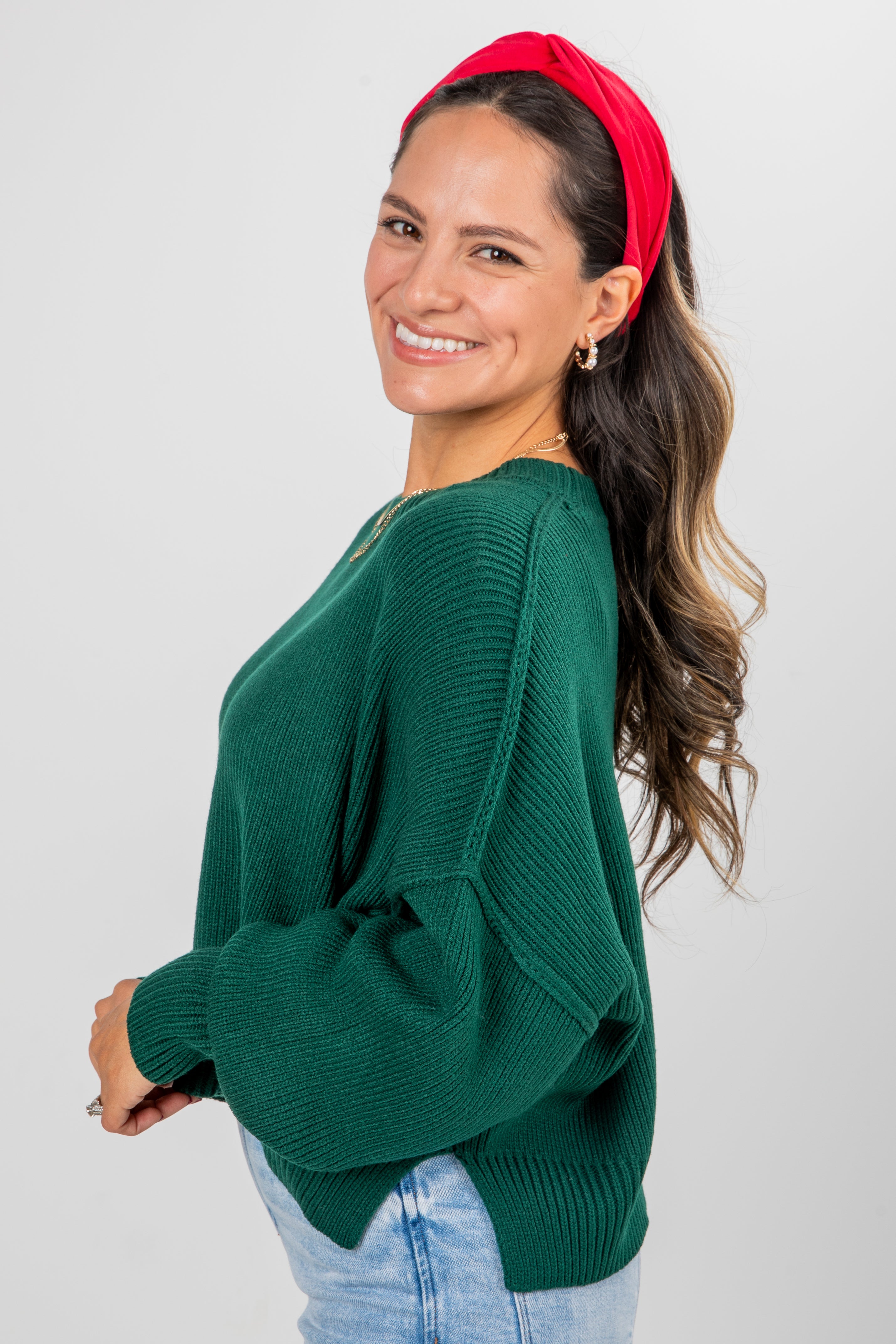 Woman wearing a green sweater and red headband on a plain background