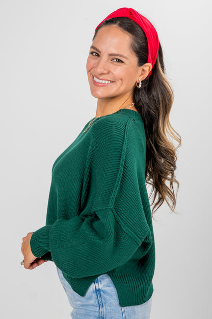 Woman wearing a green sweater and red headband on a plain background