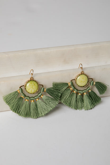 Green tassel earrings with gold accents on a light surface