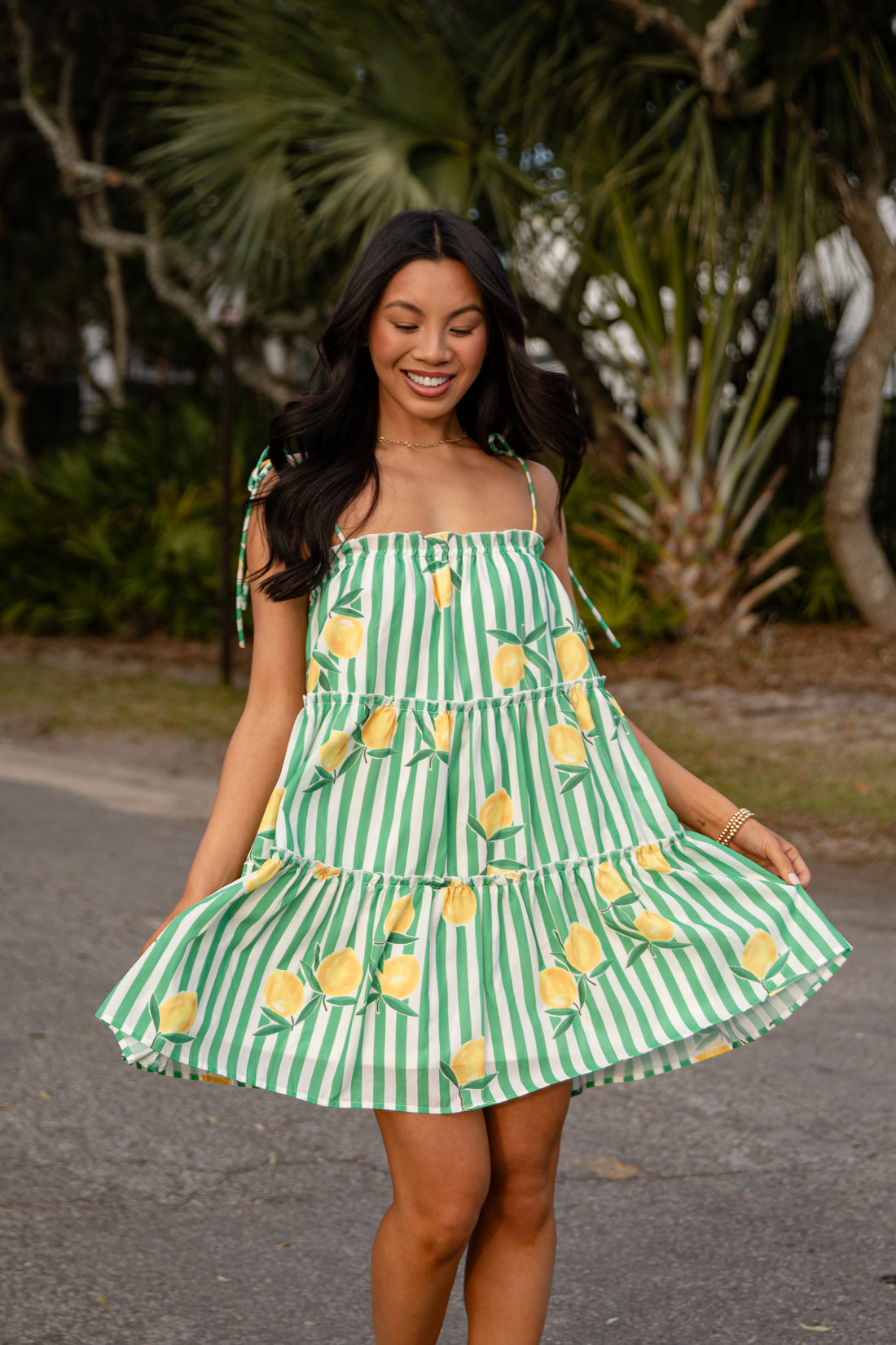 Woman wearing a green and white striped dress with yellow pineapple patterns outdoors.