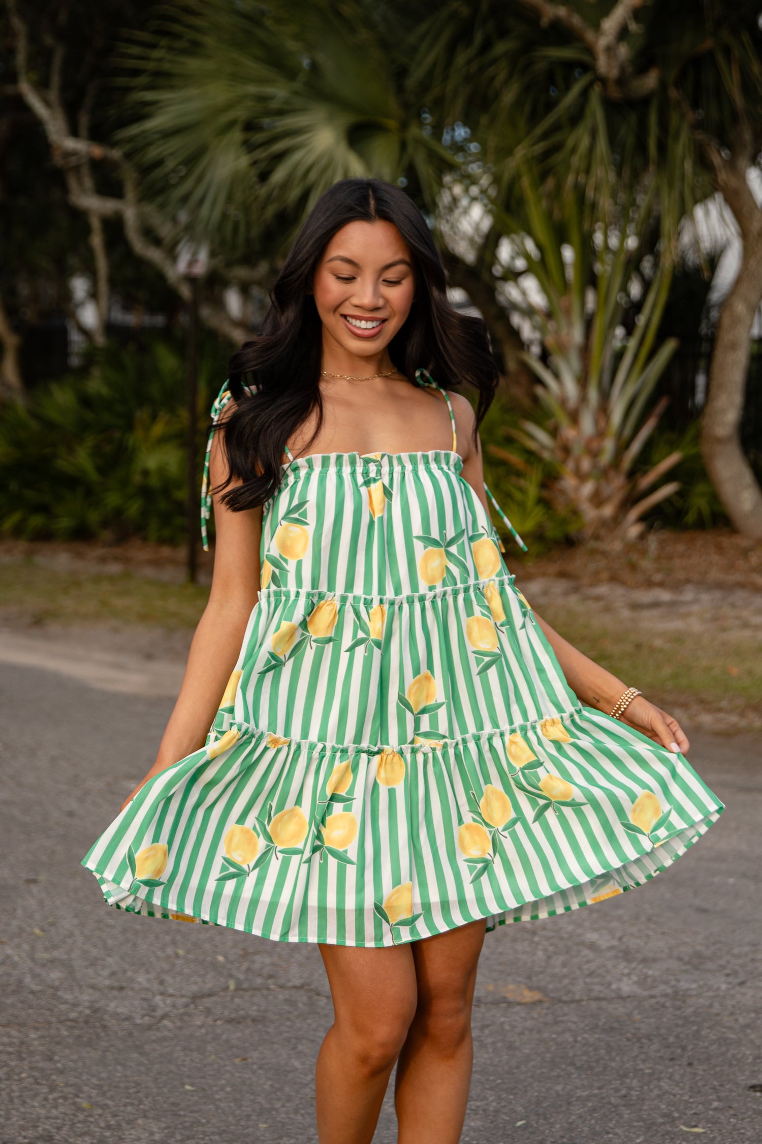 Woman wearing a green and white striped dress with yellow pineapple patterns outdoors.