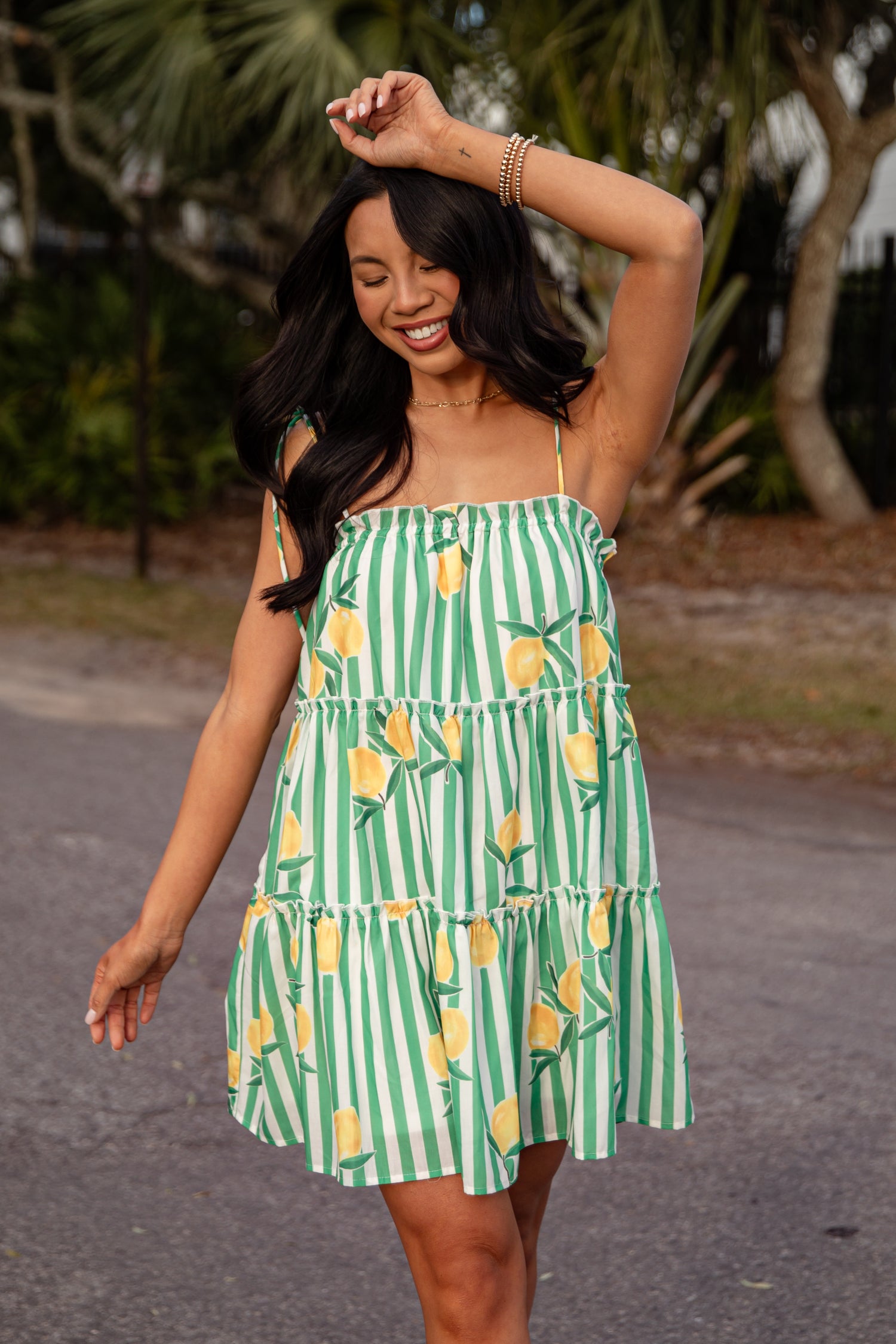 Woman wearing a green and white striped dress with pineapple pattern outdoors.