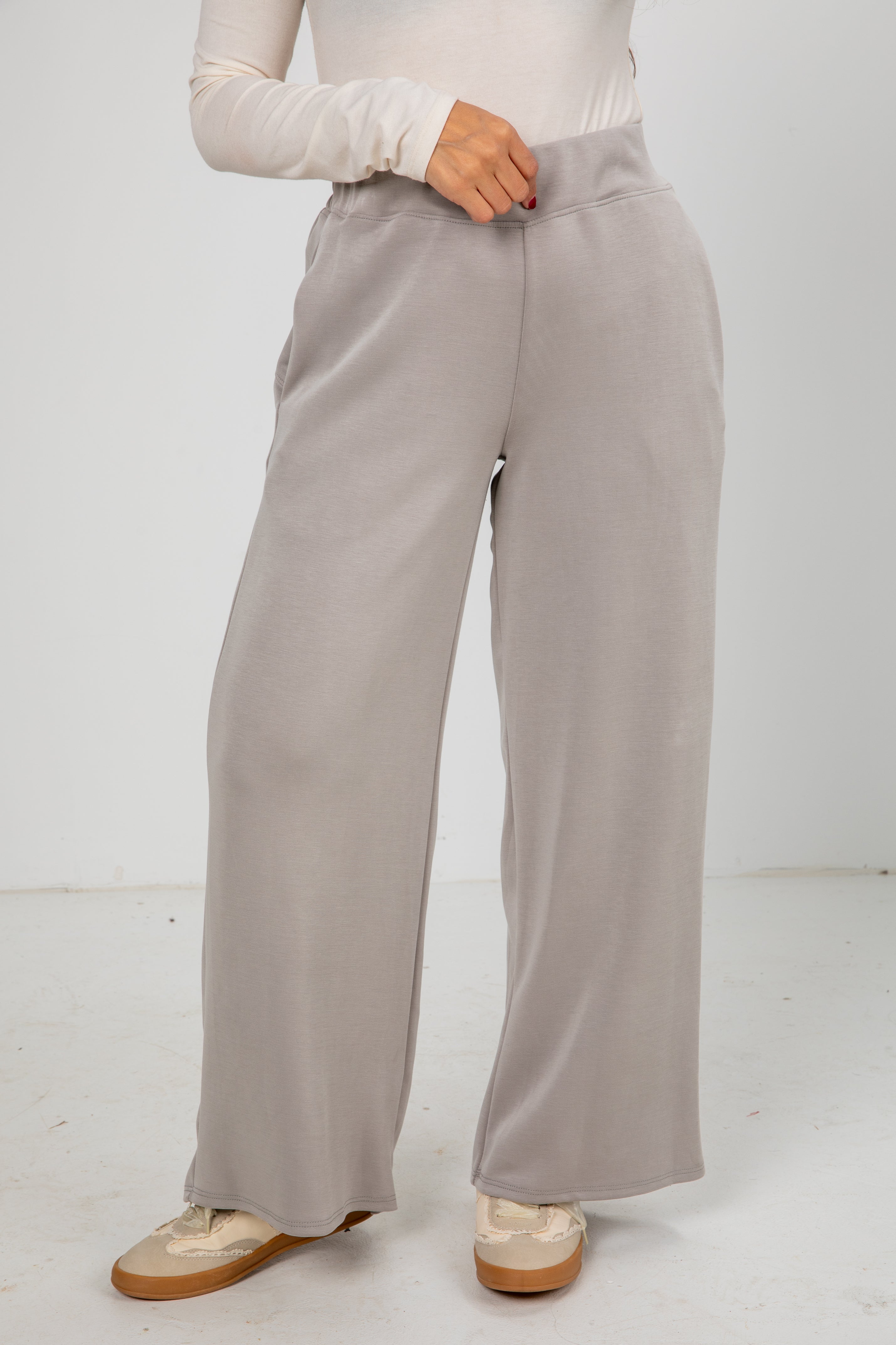 Person wearing light gray wide-leg pants on a white background