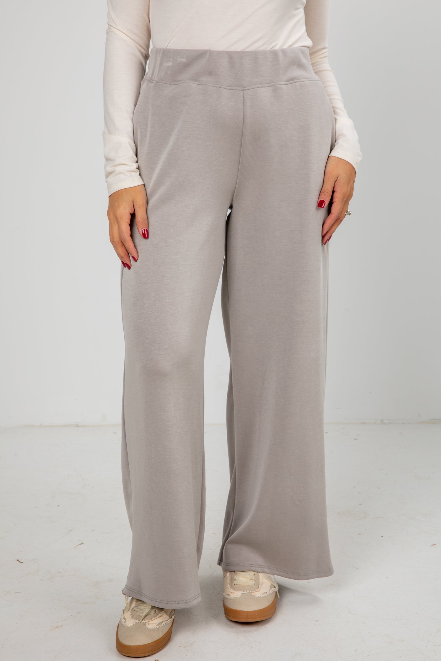 Person wearing light gray wide-leg pants on a white background