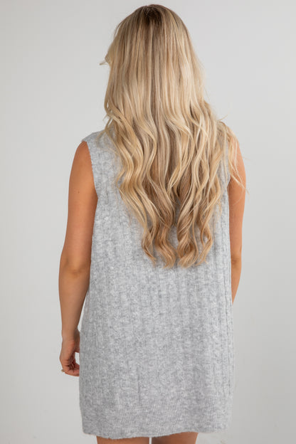 Person wearing a gray sleeveless dress with long blonde hair.