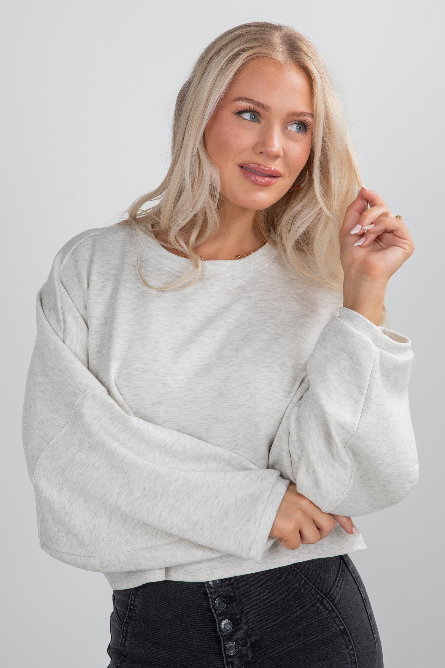 Woman wearing a light gray sweater against a plain background