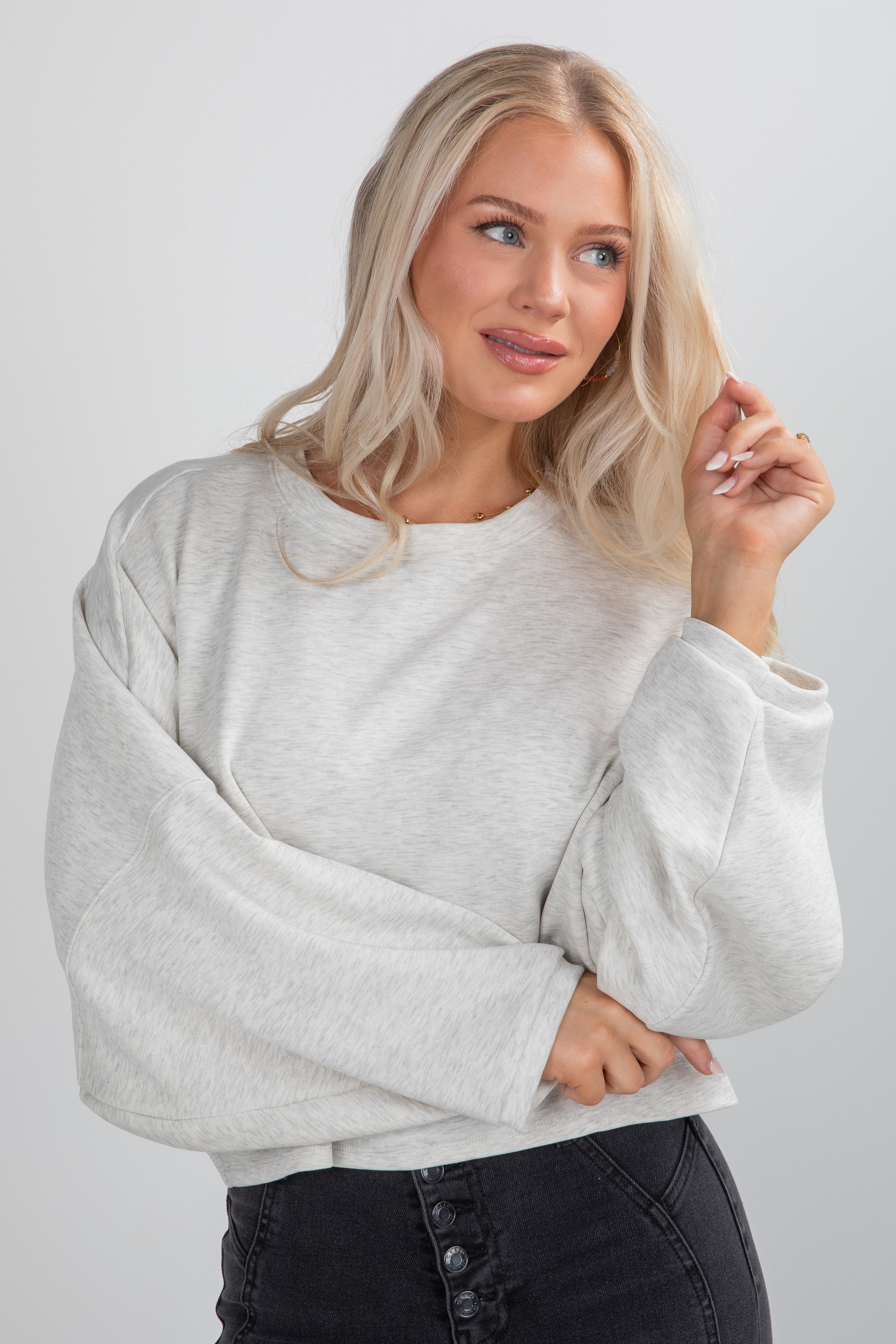 Woman wearing a light gray sweater against a plain background