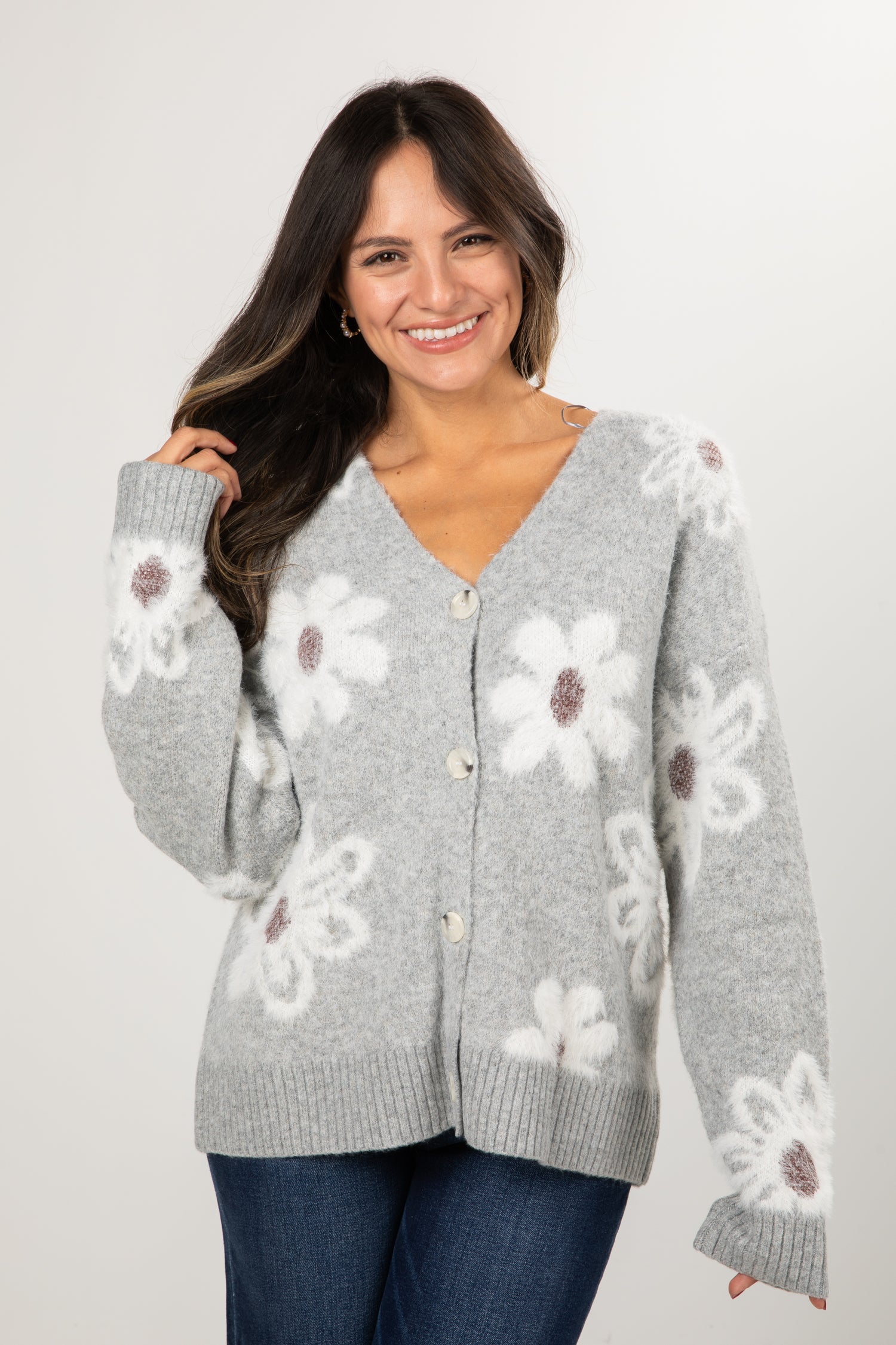 Woman wearing a gray cardigan with floral patterns on a white background