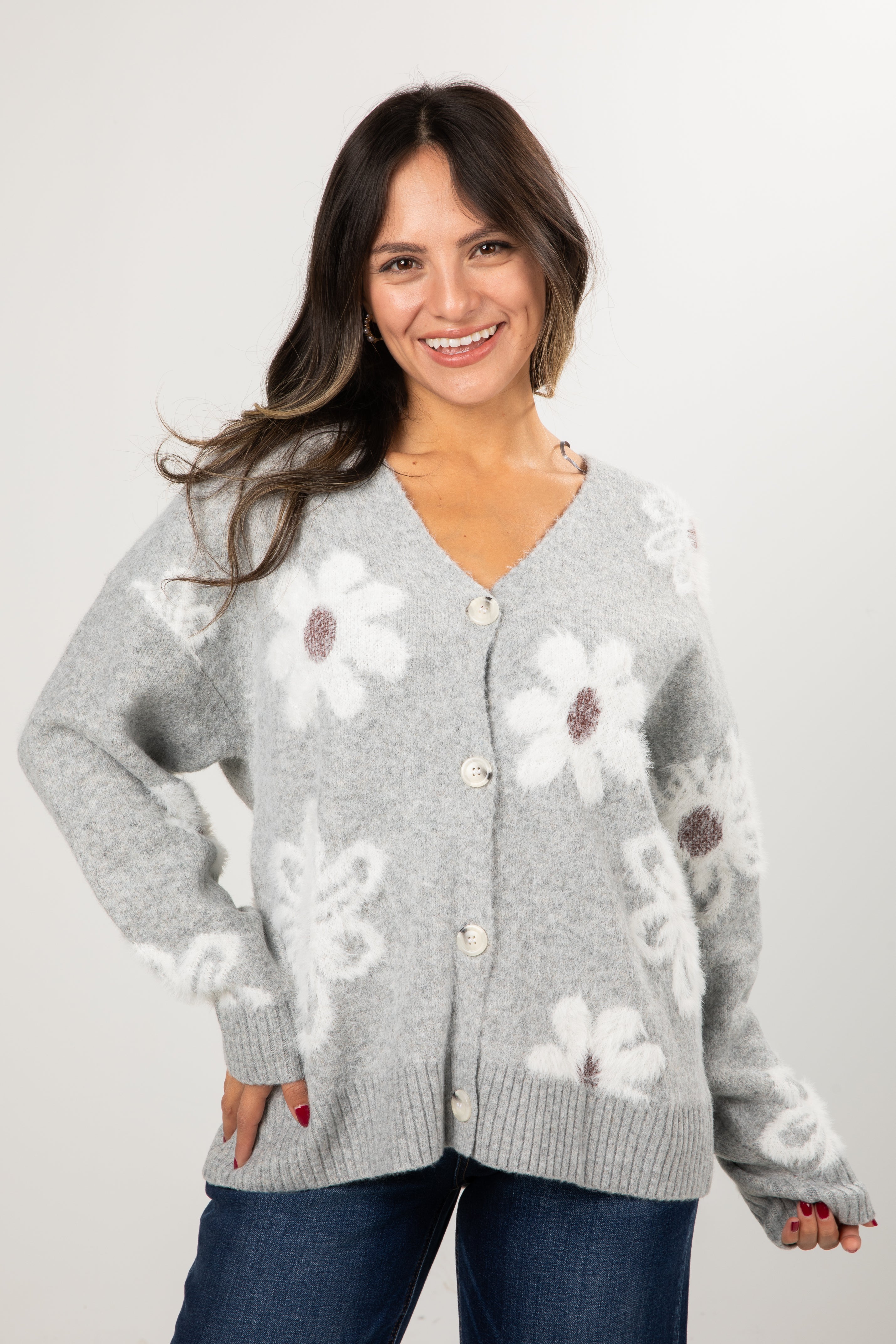 Woman wearing a gray cardigan with floral patterns on a plain background