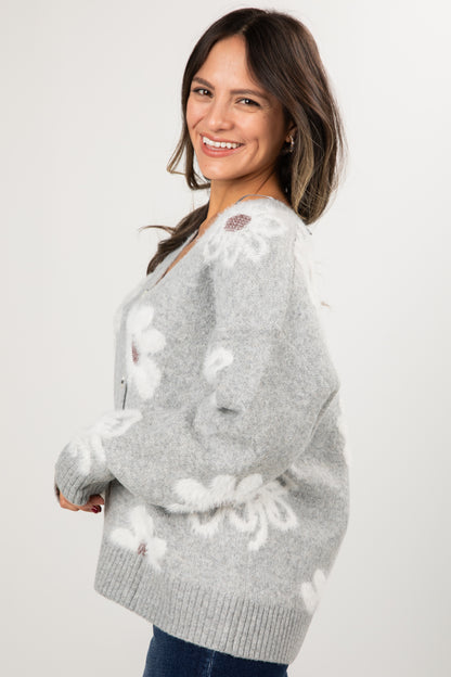 Woman wearing a gray sweater with white floral patterns on a white background