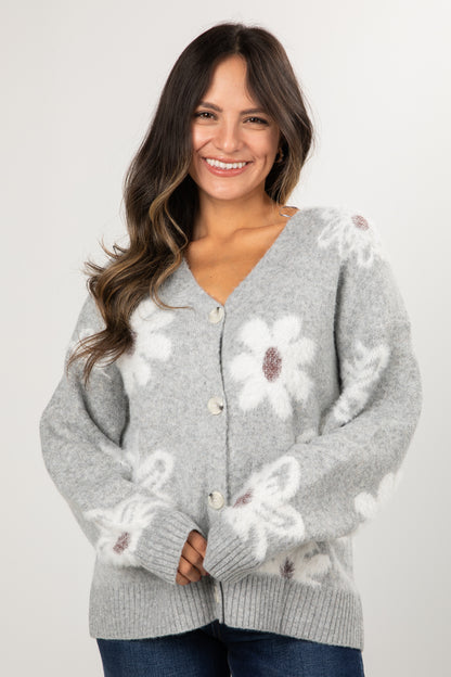 Woman wearing a gray cardigan with floral patterns on a white background