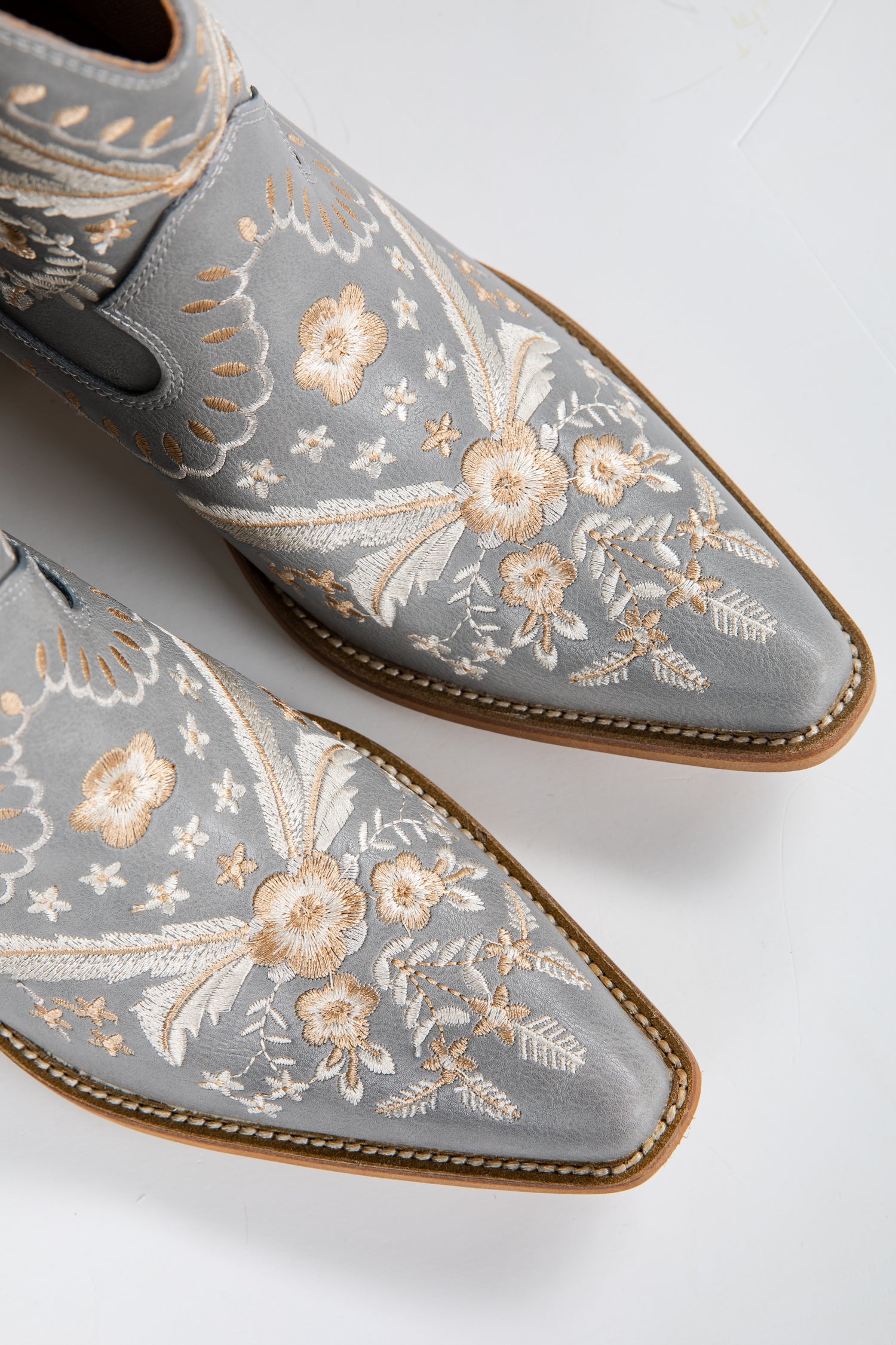 Gray embroidered shoes with floral patterns on a light gray background