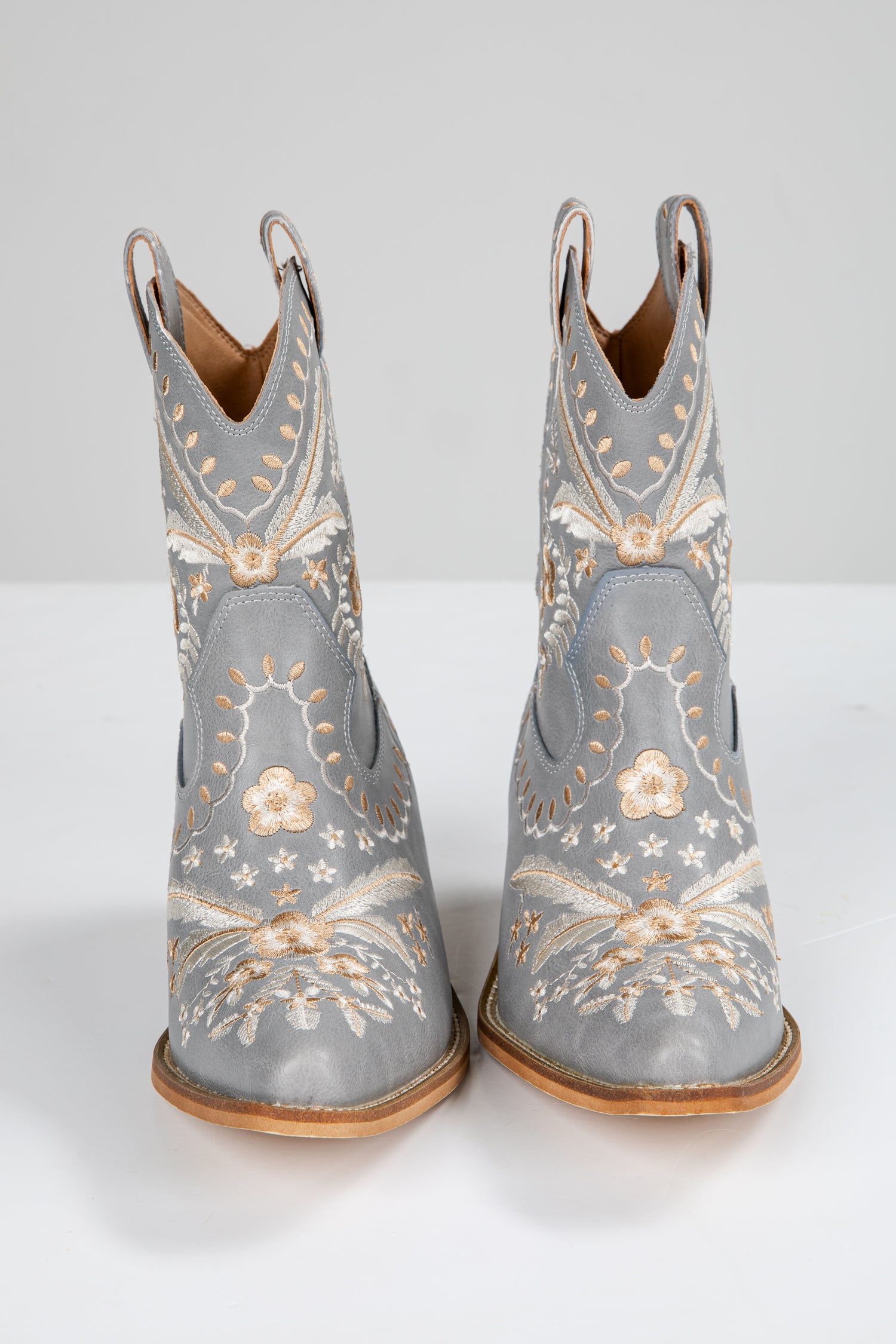 Pair of gray cowboy boots with floral embroidery on a white background