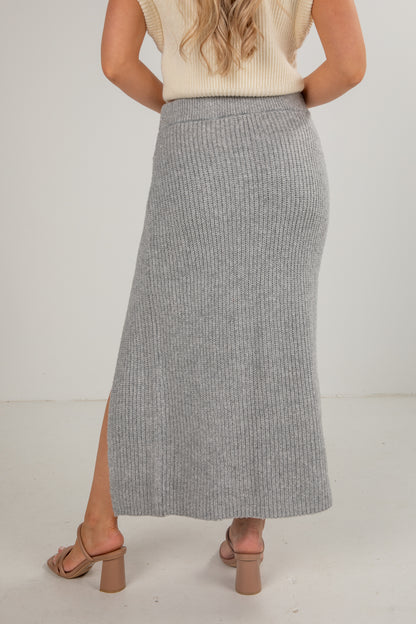 Person wearing a gray ribbed knit skirt with a white background