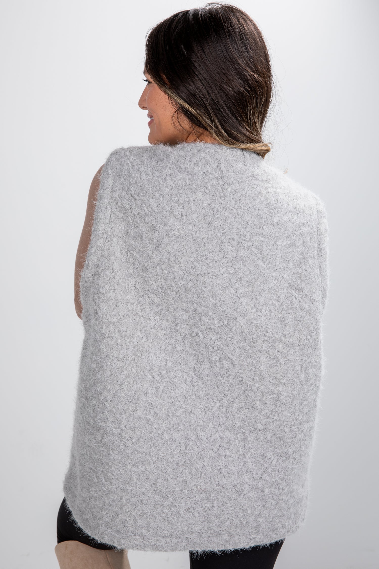Woman wearing a gray poncho against a white background