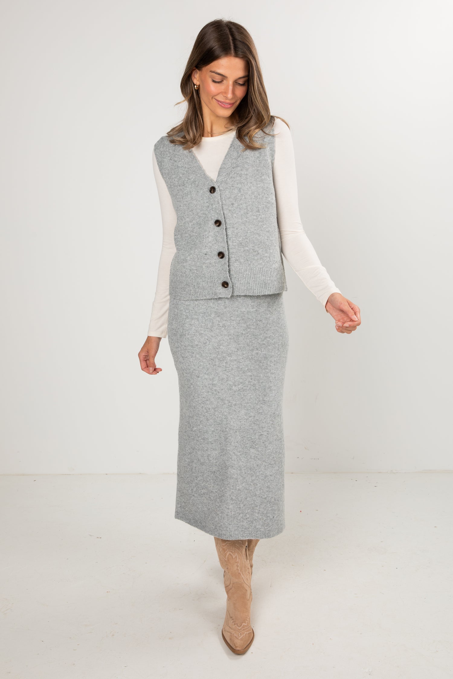Woman wearing a gray vest and skirt set on a white background