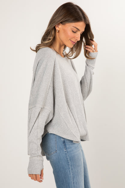 Woman wearing a gray sweater and blue jeans on a white background