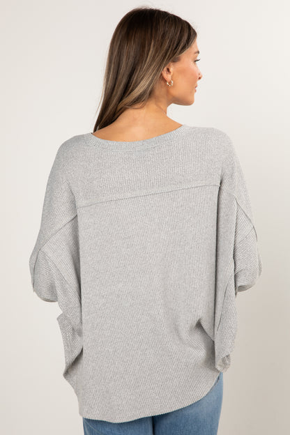 Woman wearing a gray sweater with a plain background
