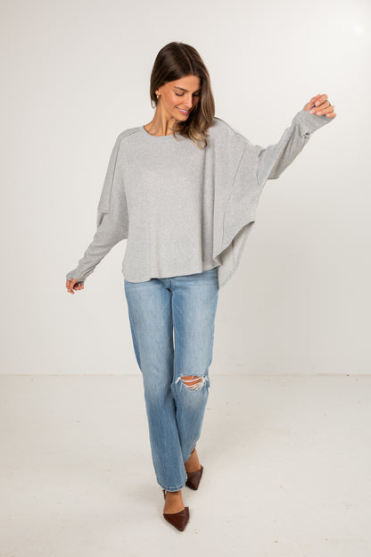 Woman wearing a gray sweater and blue jeans on a white background