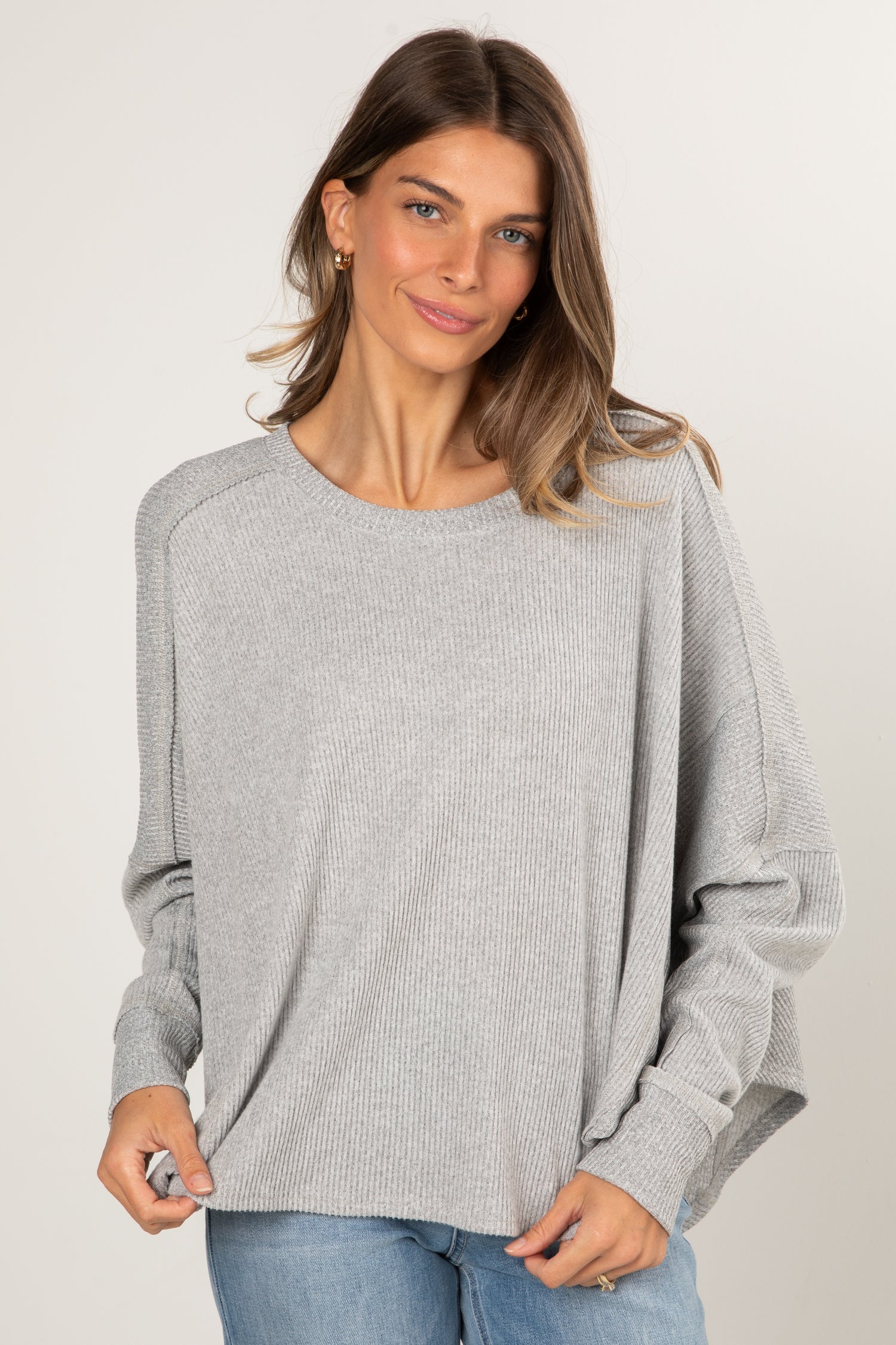 Woman wearing a gray sweater on a plain background