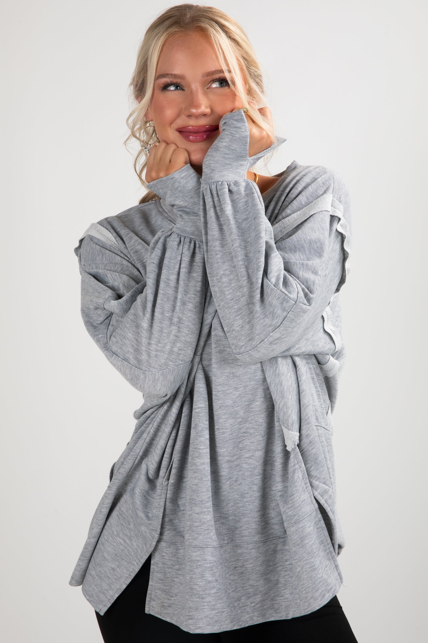 Woman wearing a gray long-sleeve top with a white background