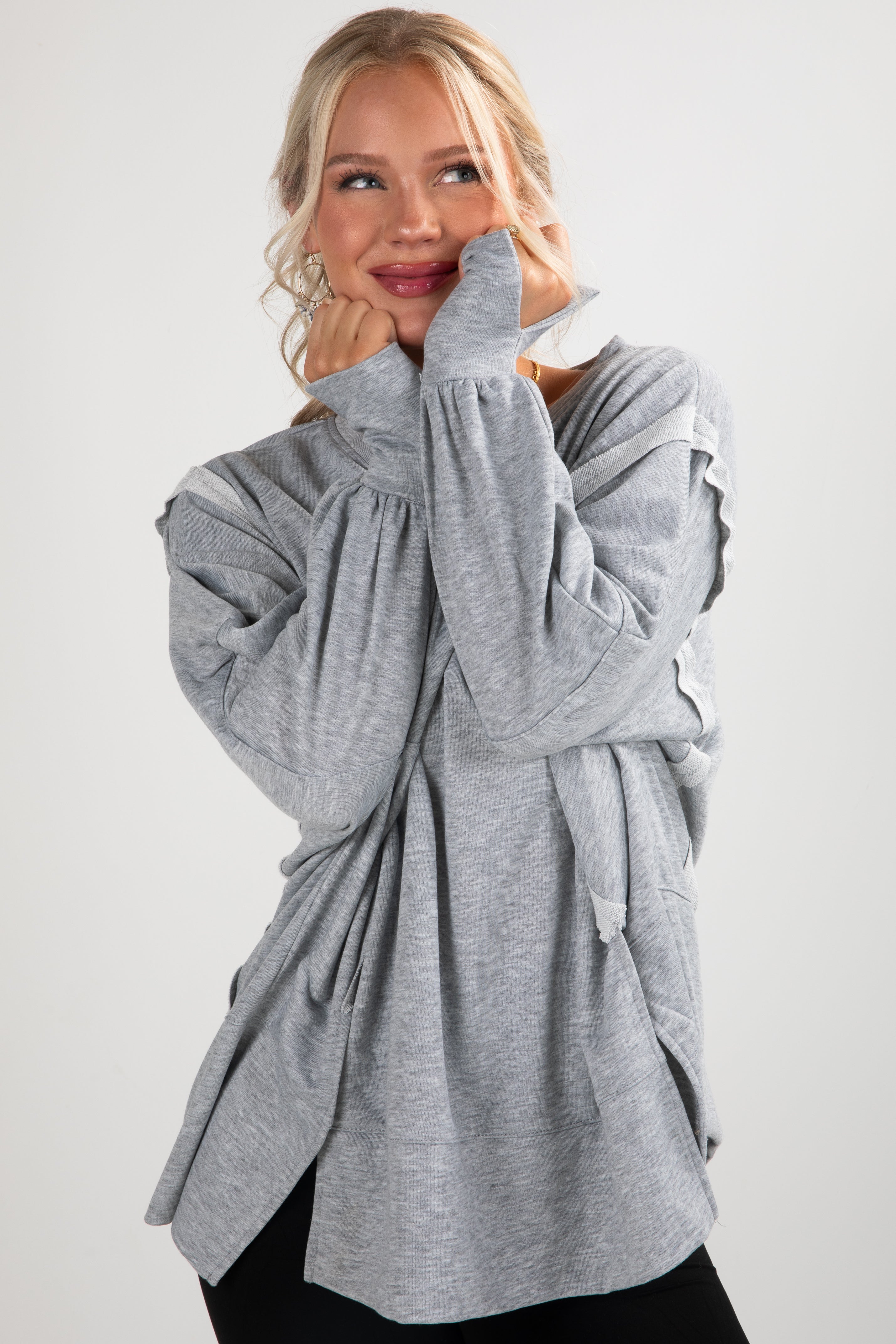 Woman wearing a gray long-sleeve top with a white background