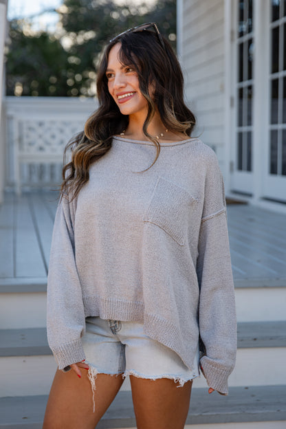 Woman wearing a beige sweater and shorts standing outdoors.