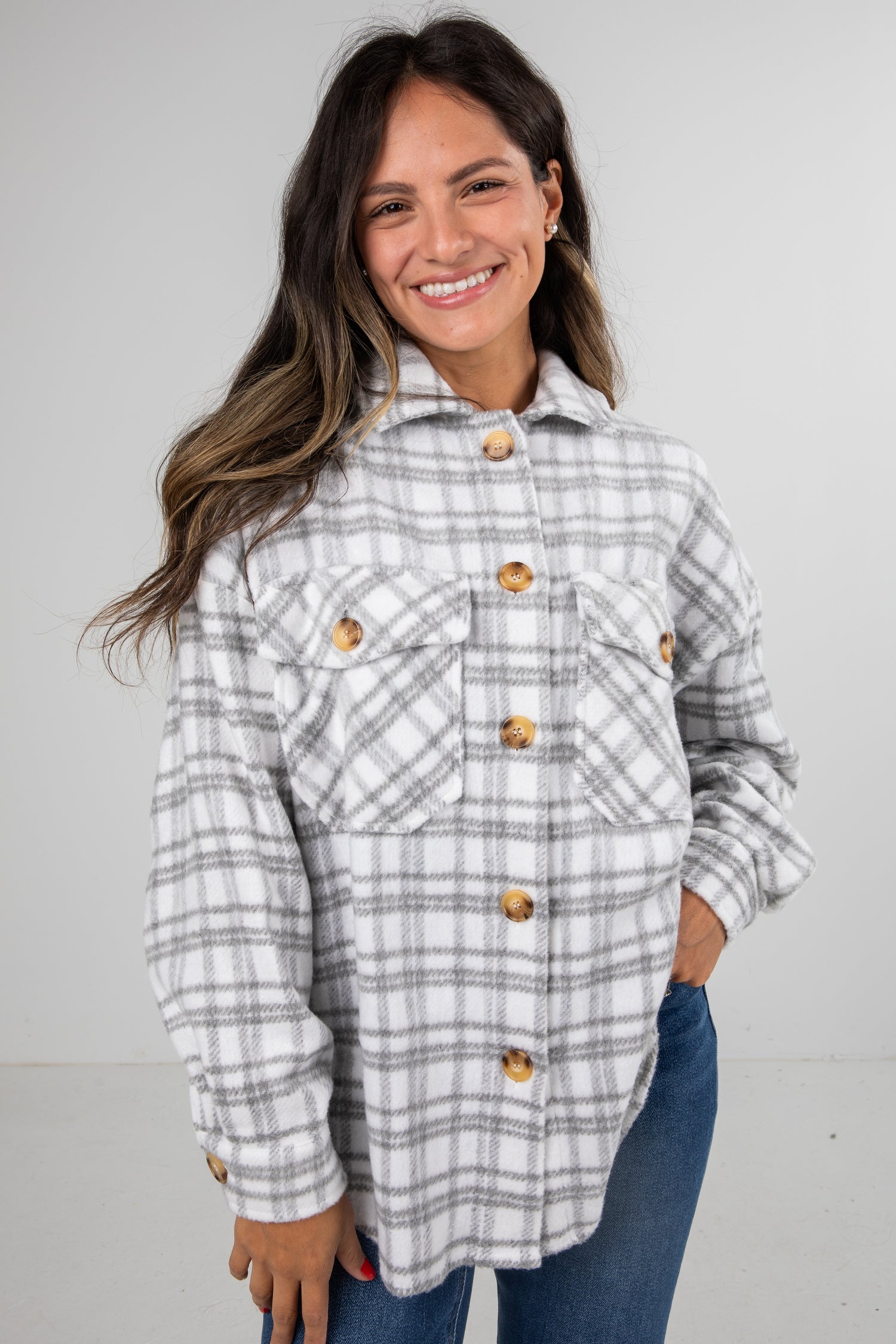 Woman wearing a plaid shirt with buttons against a plain background