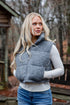 Woman wearing a gray puffer vest outdoors in a forest setting