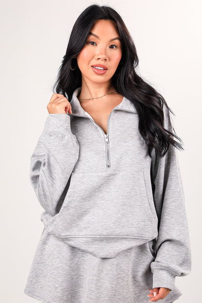 Woman wearing a gray pullover with a zipper on a white background