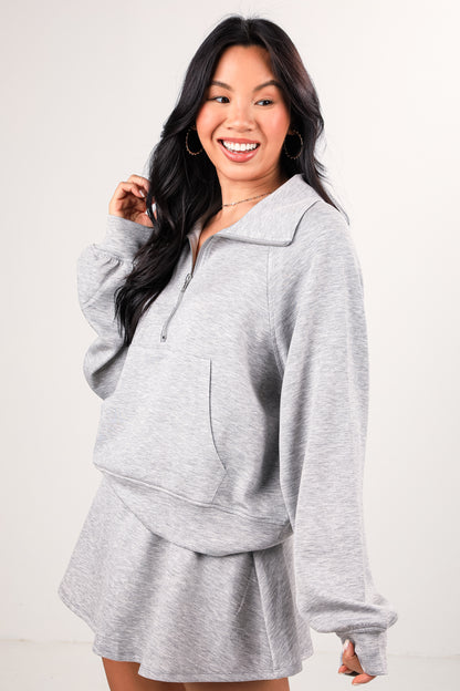 Woman wearing a gray outfit with a matching jacket and shorts on a white background