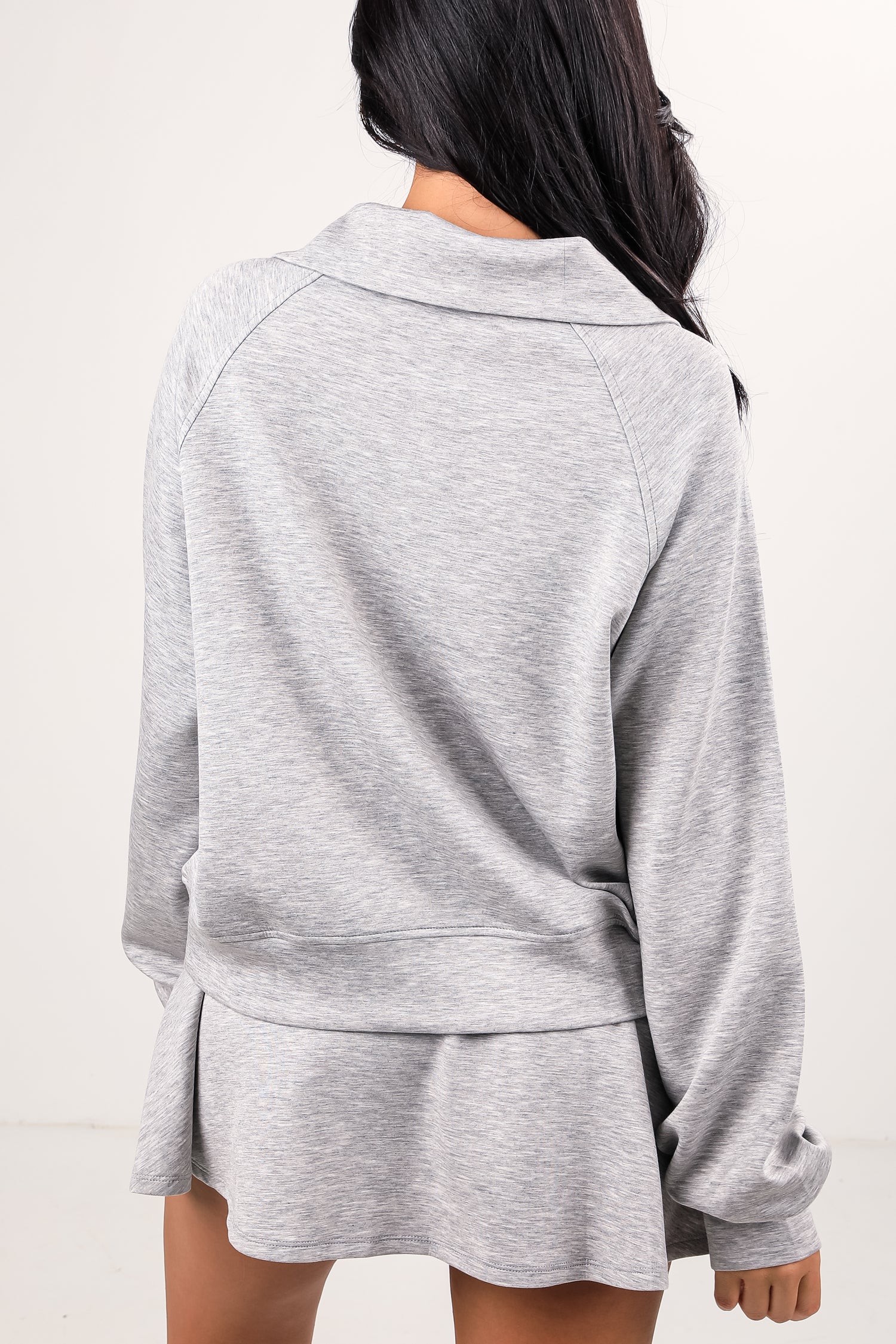 Person wearing a gray tracksuit on a white background