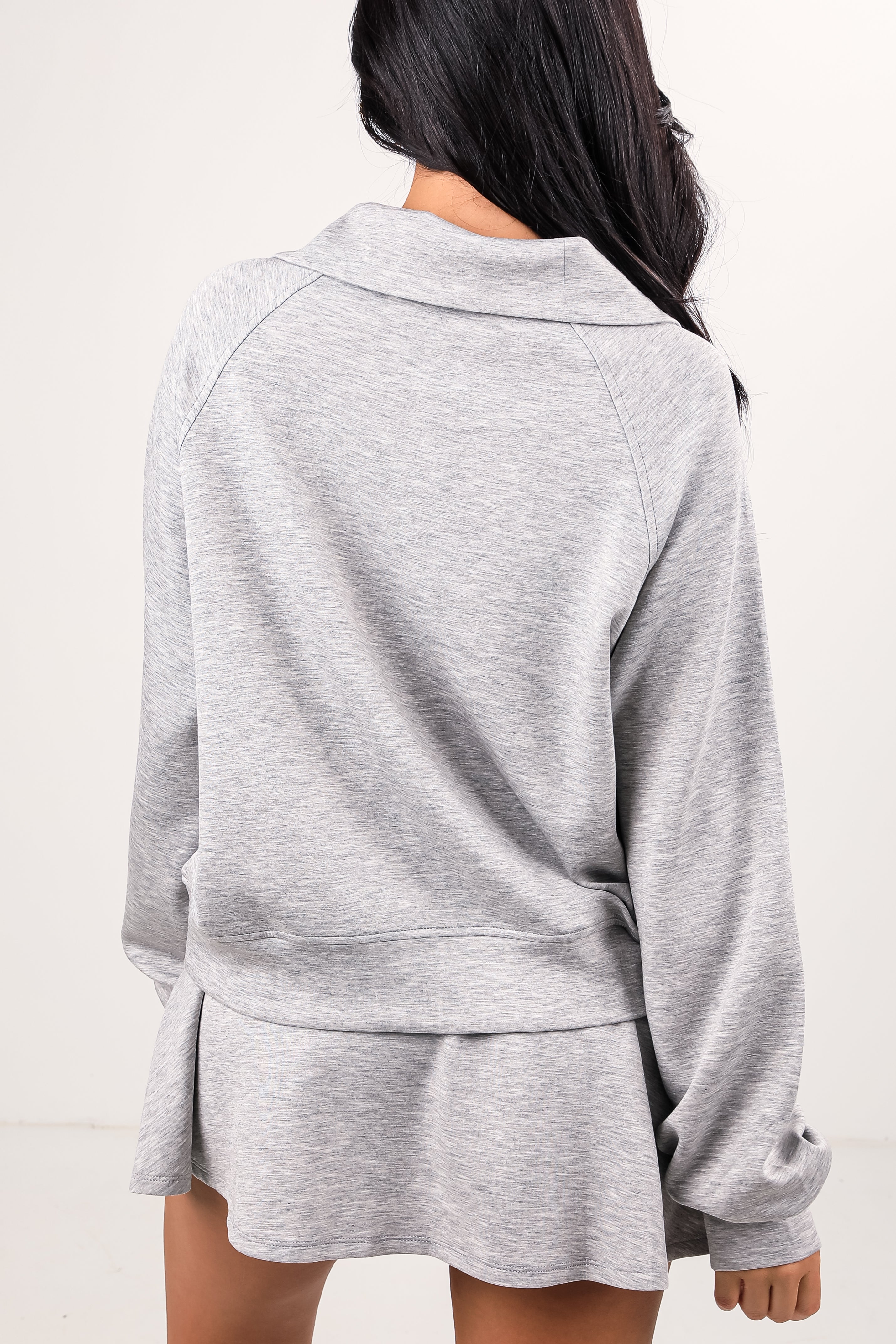 Person wearing a gray tracksuit on a white background