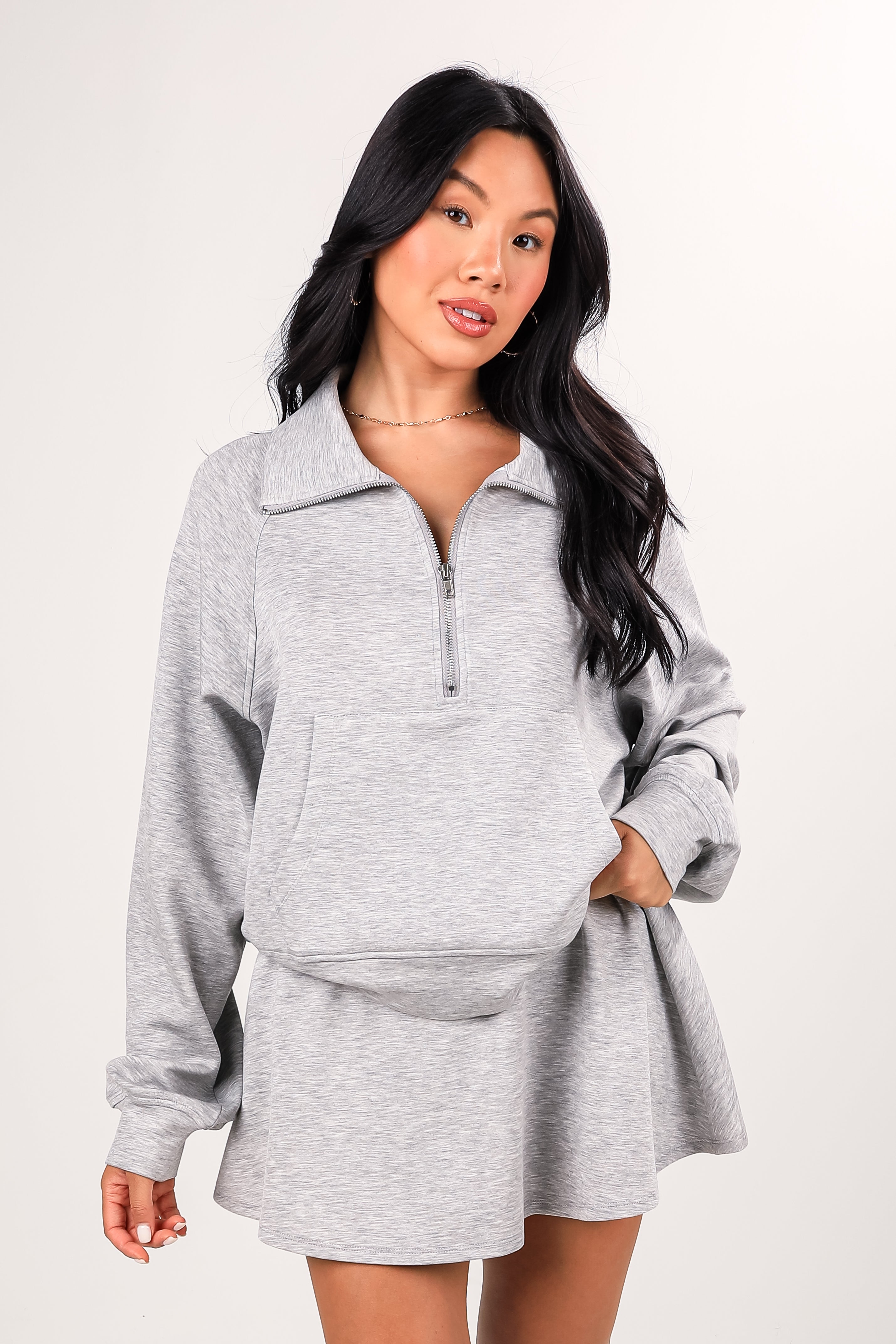 Woman wearing a gray outfit with a matching jacket and skirt on a white background