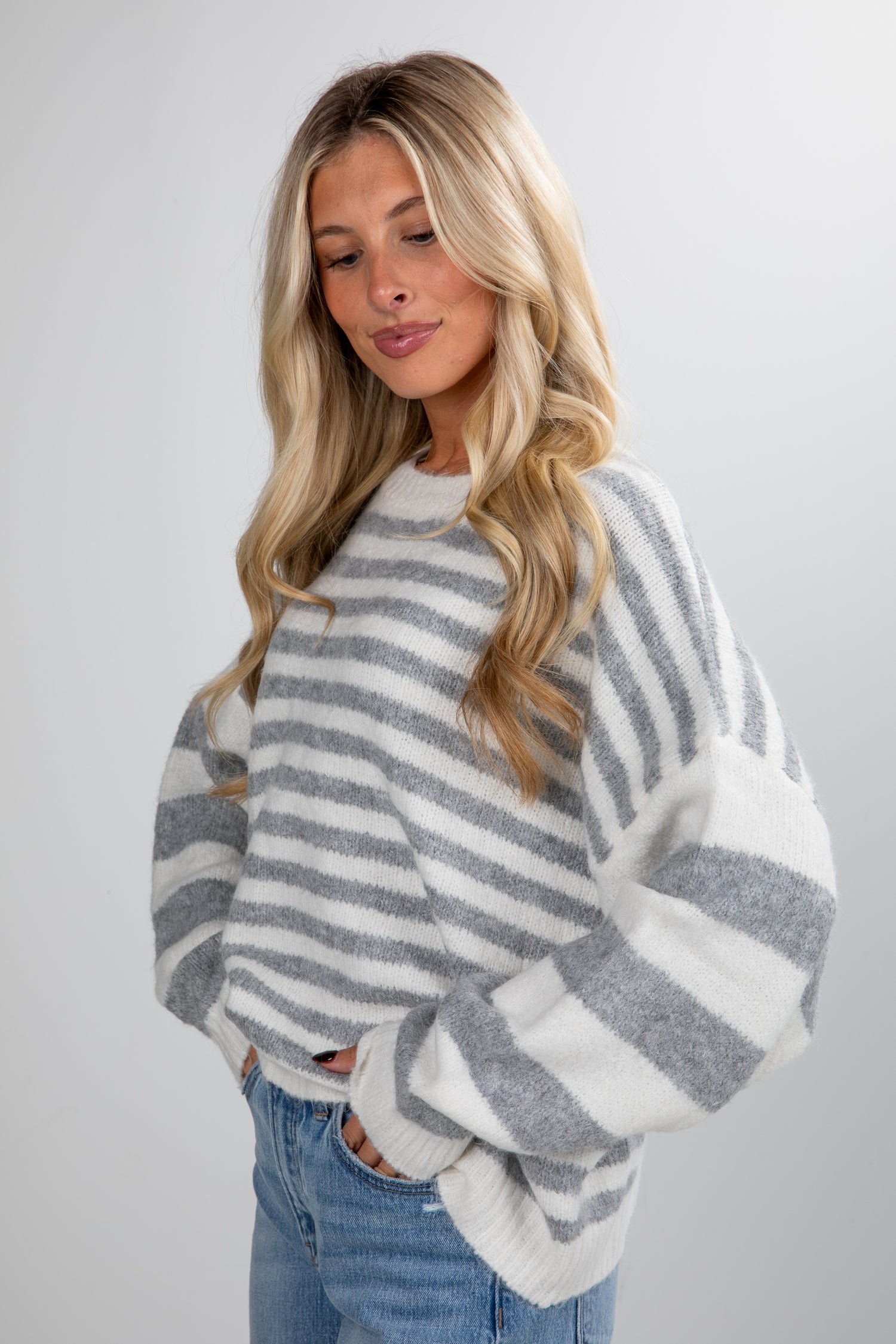 Woman wearing a gray and white striped sweater against a plain background