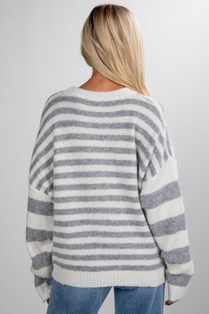 Person wearing a gray and white striped sweater on a plain background