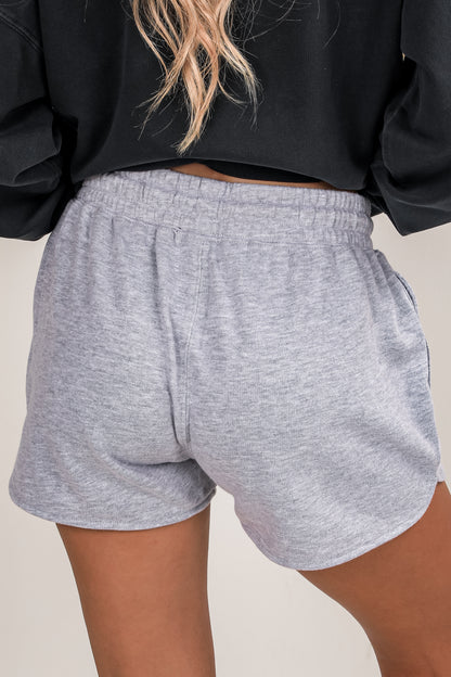 Gray shorts worn by a person on a plain background